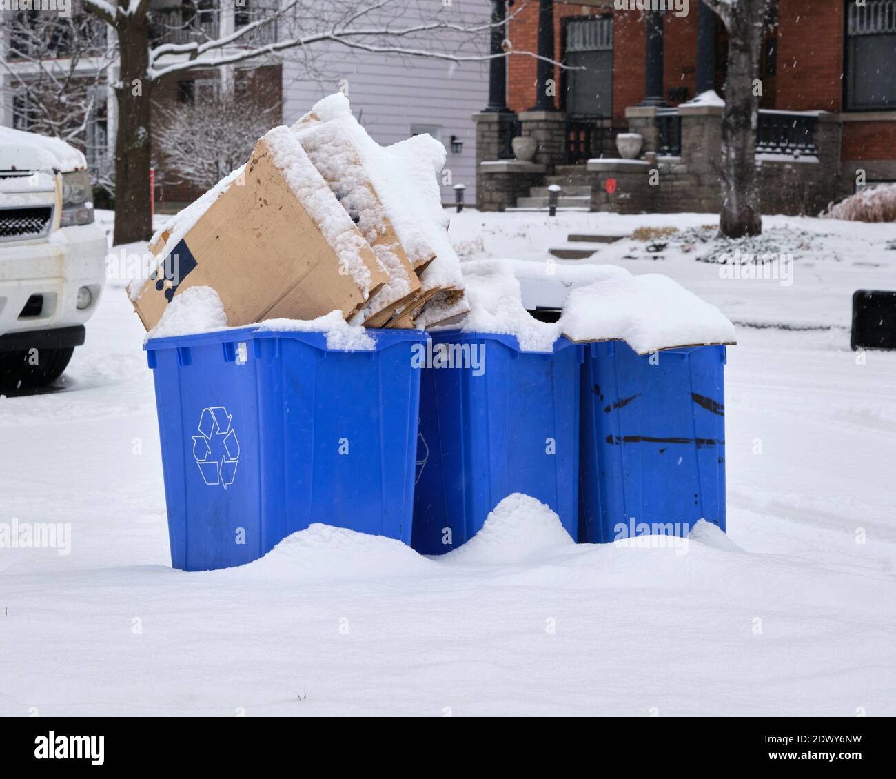 Recyclage du papier de la boîte bleue remplie sur le trottoir, restes pour la collecte le jour de neige lourde, couvrant le contenu. À Ottawa Banque D'Images