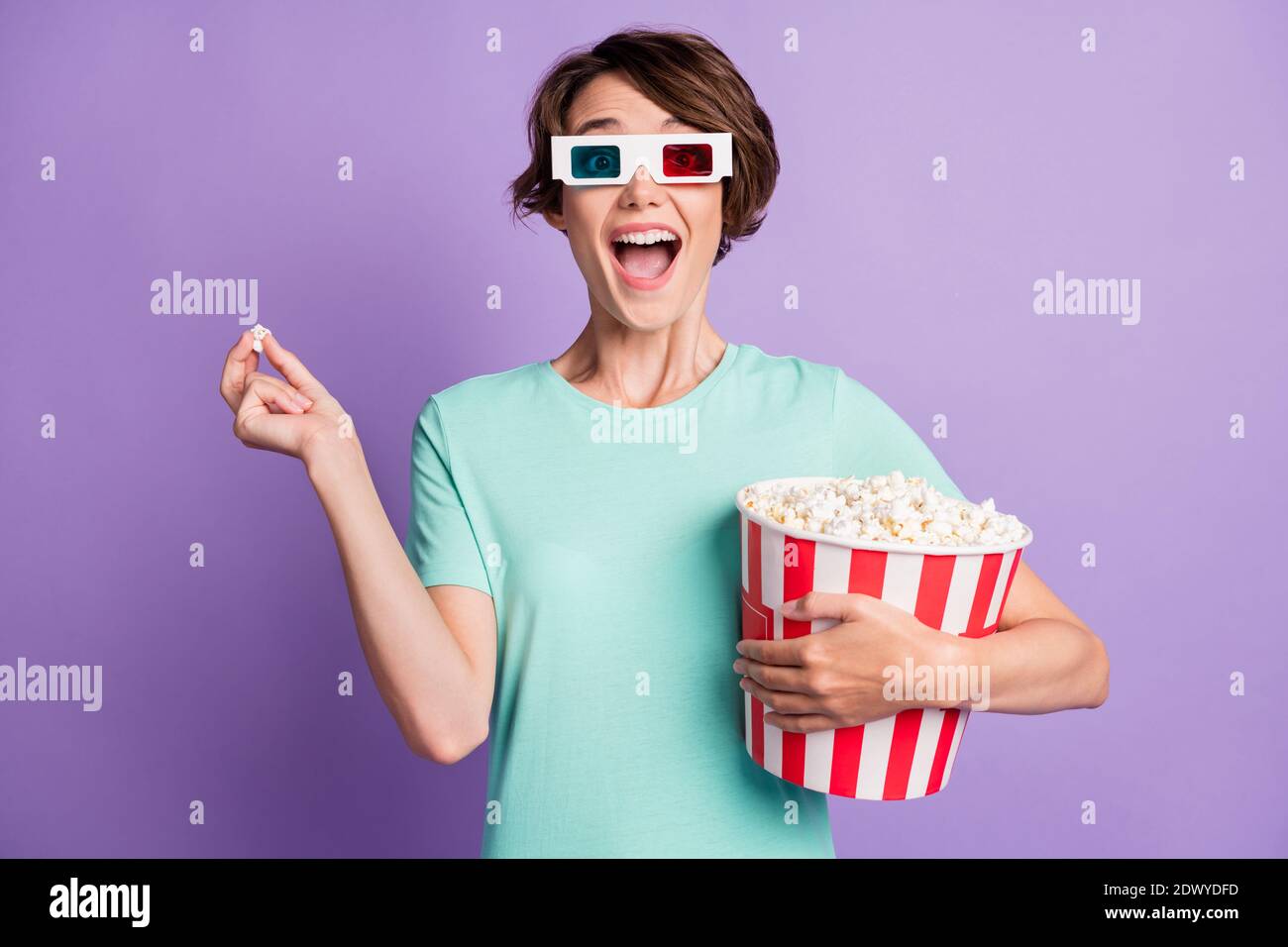 Photo de charmante jeune femme habillé décontracté turquoise vêtements 3d  lunettes de cinéma mangeant du pop-corn isolé couleur violet fond Photo  Stock - Alamy