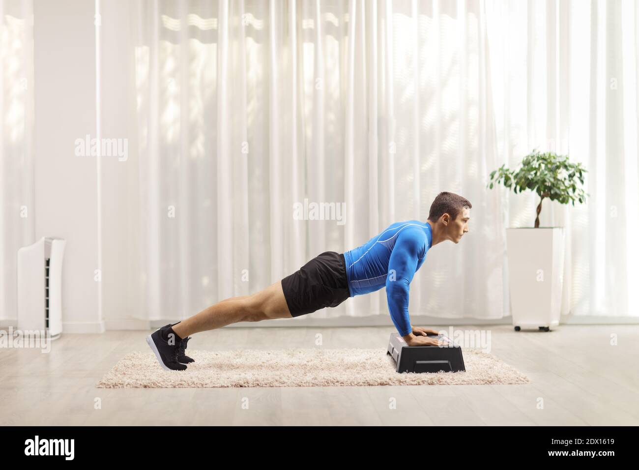 Jeune homme exerçant des push-ups sur une plate-forme aérobie de pas à accueil Banque D'Images