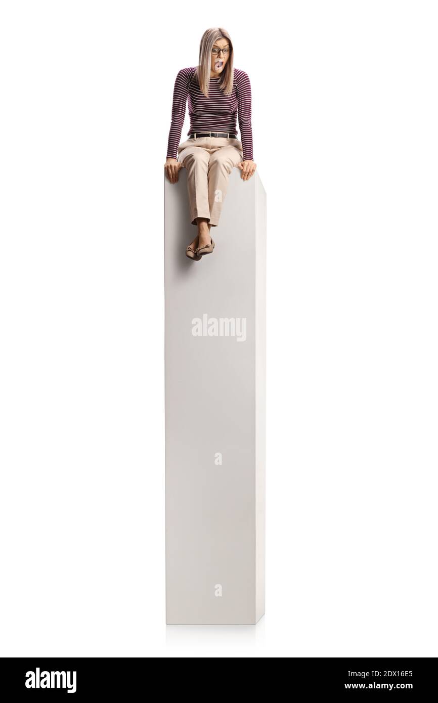 Une jeune femme effrayée assise sur une grande colonne blanche et en regardant vers le bas, isolé sur fond blanc Banque D'Images