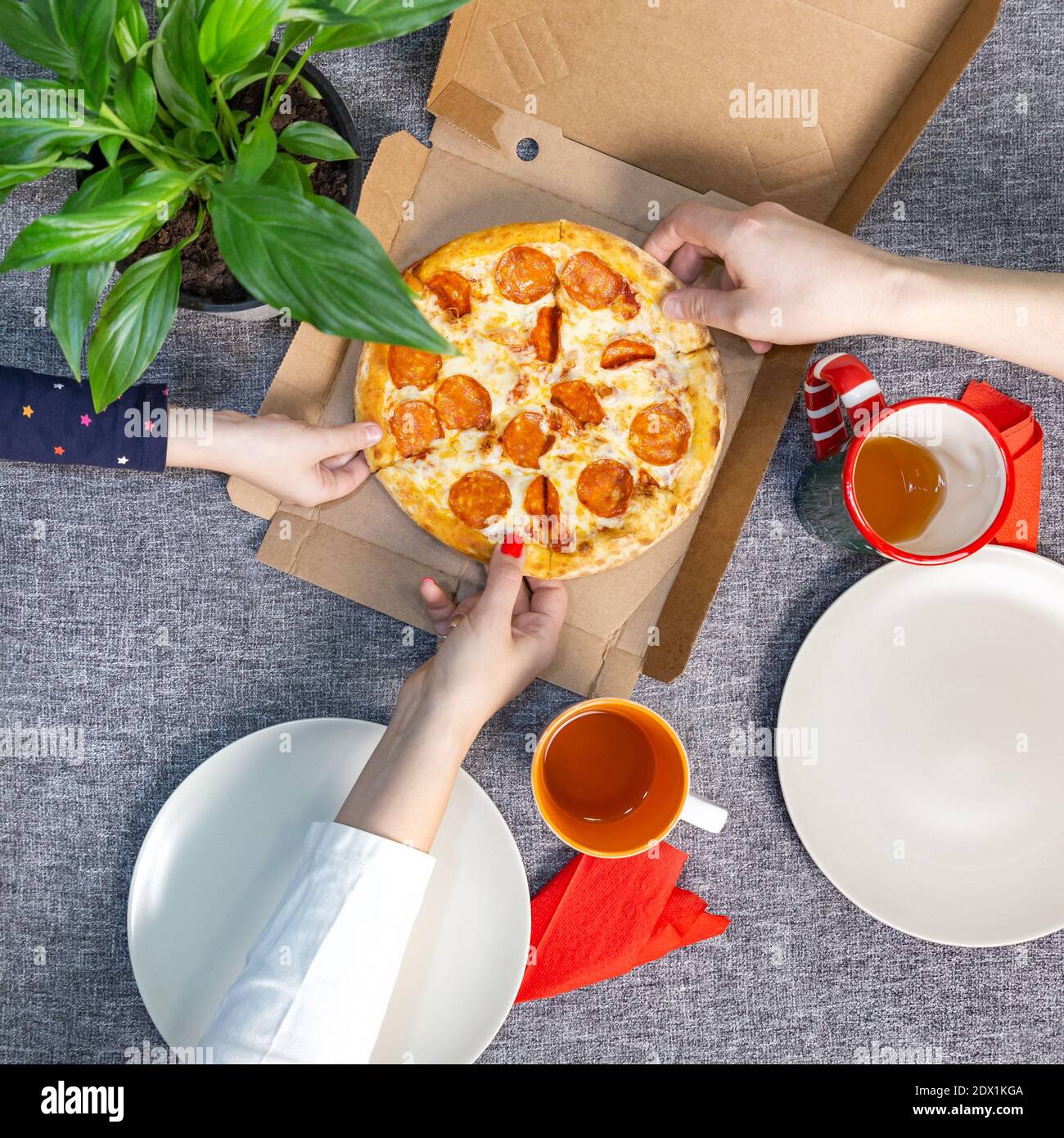 Petite pizza poivrée dans une boîte sur une table, vue de dessus, déjeuner en famille. Banque D'Images