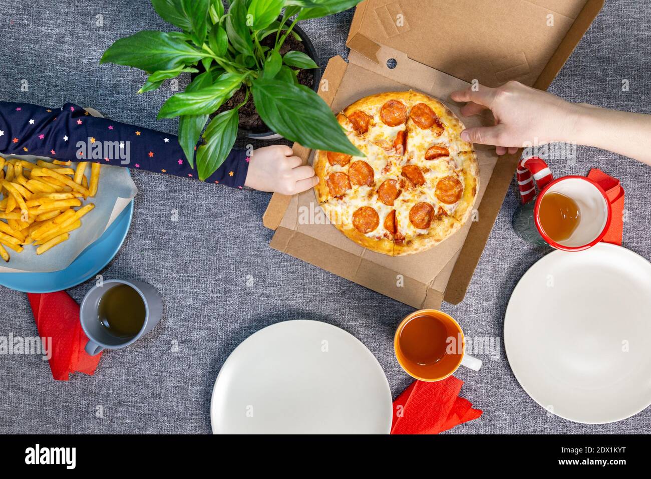 Petite pizza poivrée dans une boîte sur une table, vue de dessus, déjeuner en famille. Banque D'Images