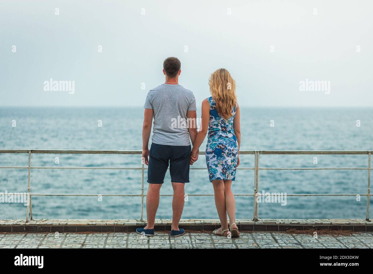 Jeune couple debout sur la rive tenant les mains et appréciant vue sur la mer Banque D'Images