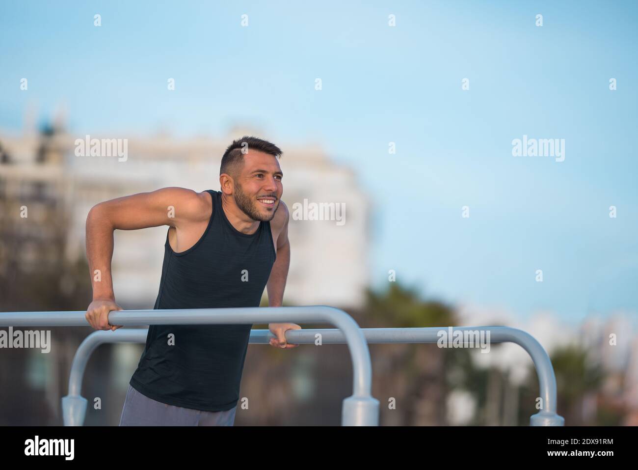 S'adapte à l'homme faisant des creux triceps sur des barres parallèles à l'extérieur. Effectuer des exercices sur des barres parallèles Banque D'Images