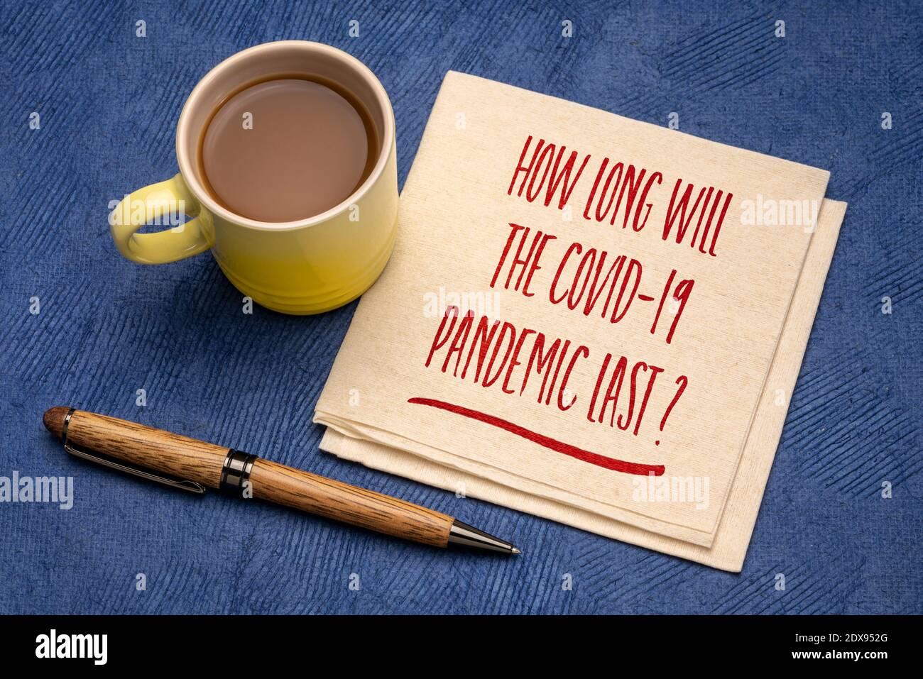 Combien de temps la pandémie de Covid-19 durera-t-elle? Écriture manuscrite sur une serviette avec une tasse de café. Concept et incertitude de l'éclosion du coronavirus. Banque D'Images