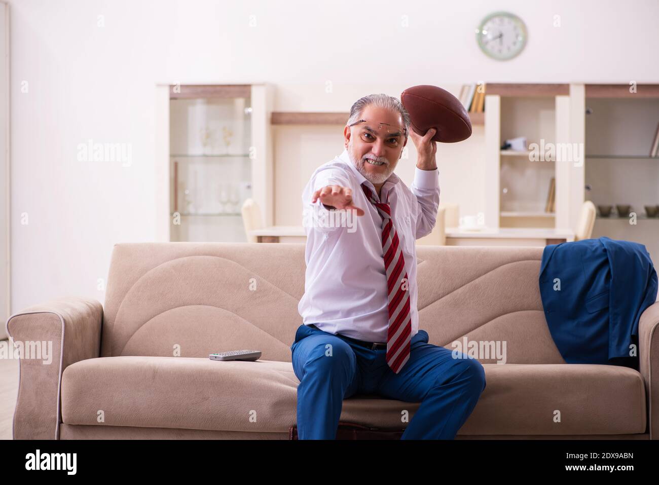 Un patron masculin senior lance un ballon de rugby à la maison Photo Stock  - Alamy