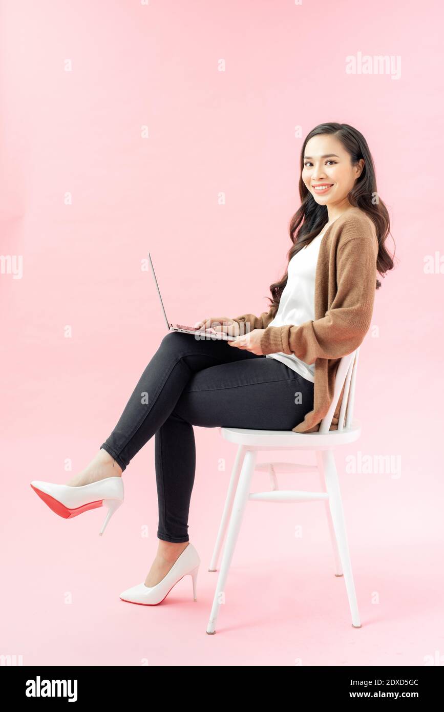 Jeune femme asiatique adolescente souriante assise sur une chaise à l'aide d'un ordinateur portable pour le travail de la maison sur covid-19 coronavirus crysis, Banque D'Images