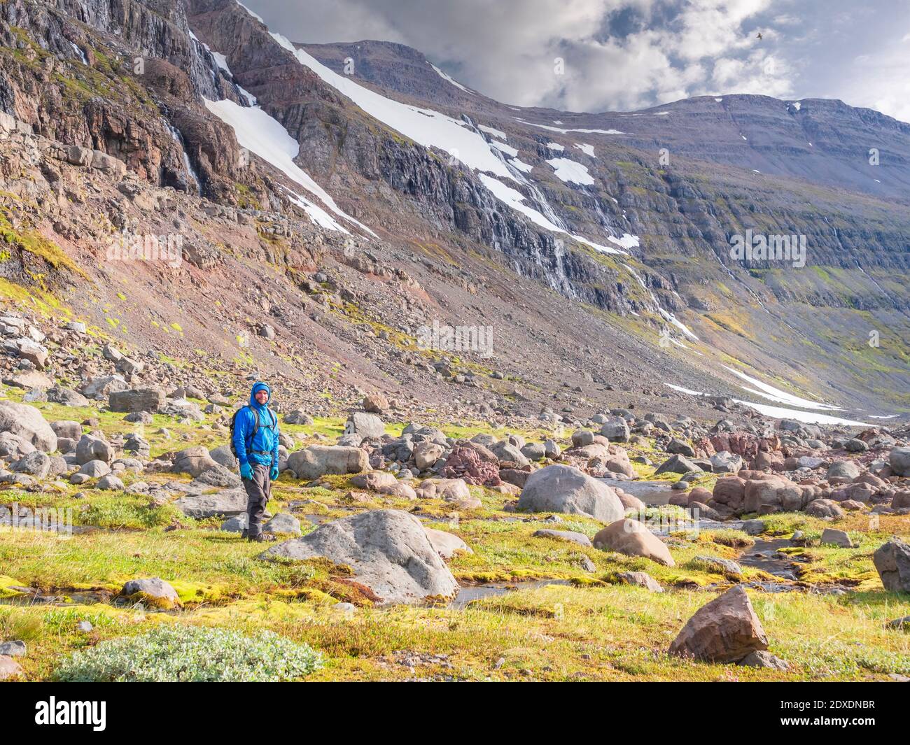 Randonneur mâle debout au milieu des rochers dans la vallée islandaise Banque D'Images