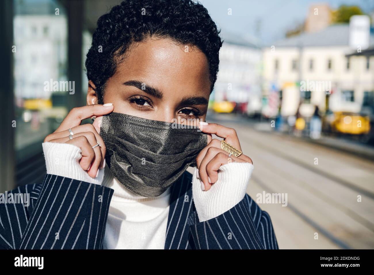 Jeune femme d'affaires portant un masque de protection à l'arrêt de bus on jour ensoleillé Banque D'Images