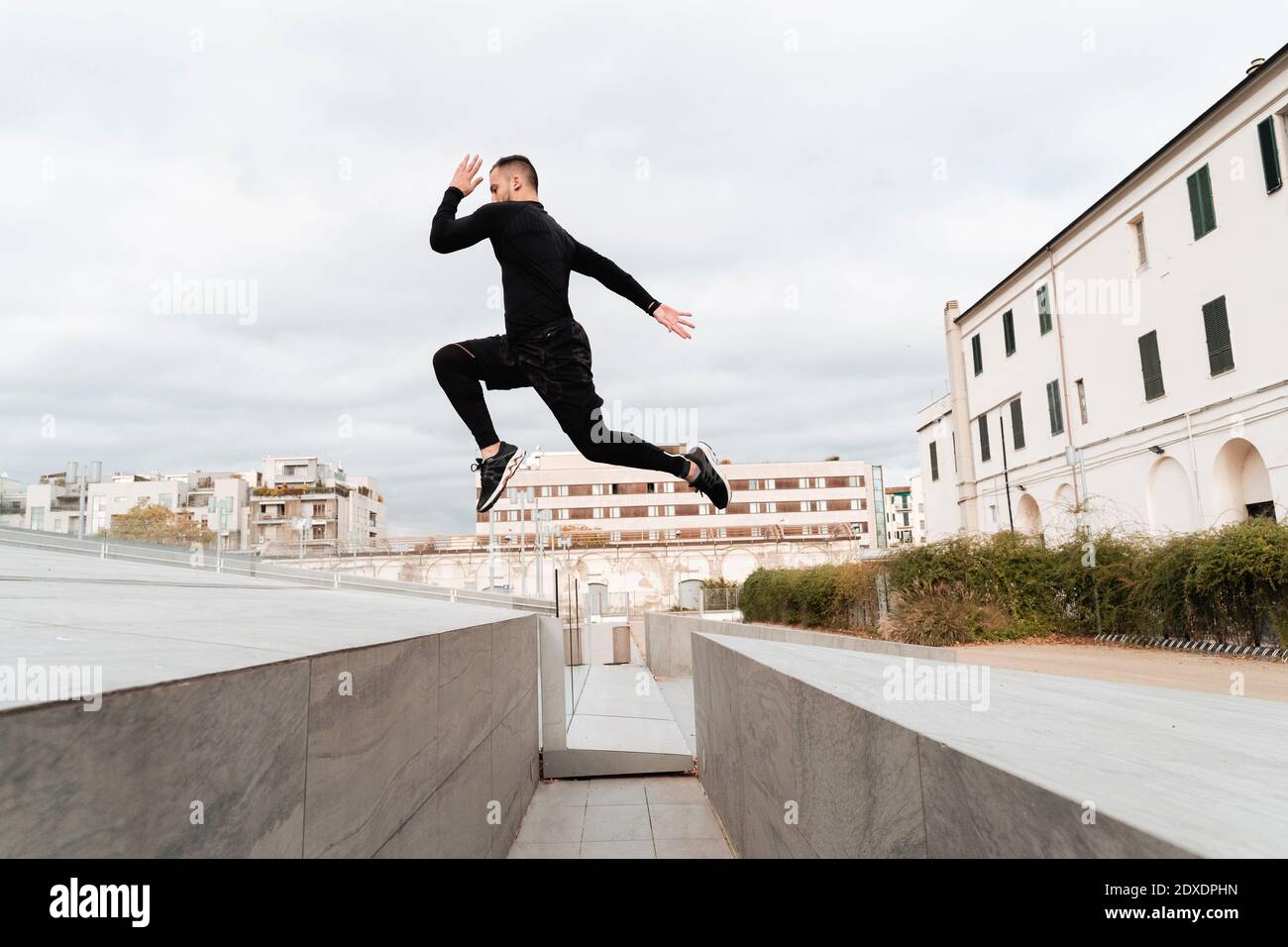 Homme sautant sur le mur contre un ciel dégagé Banque D'Images
