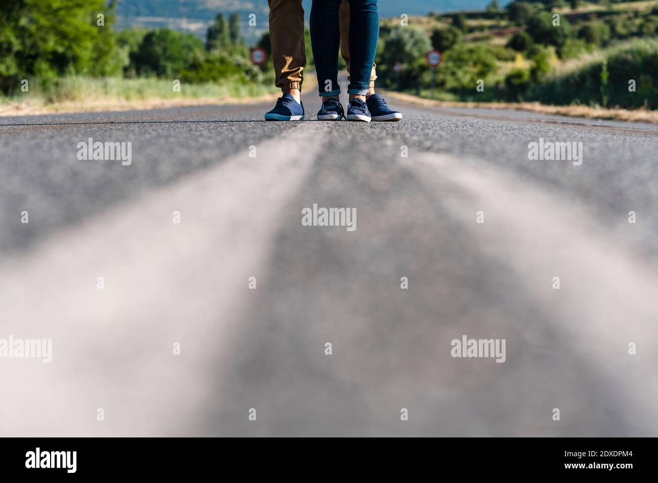 Jeune couple debout au milieu de la route sur la route ensoleillée Banque D'Images