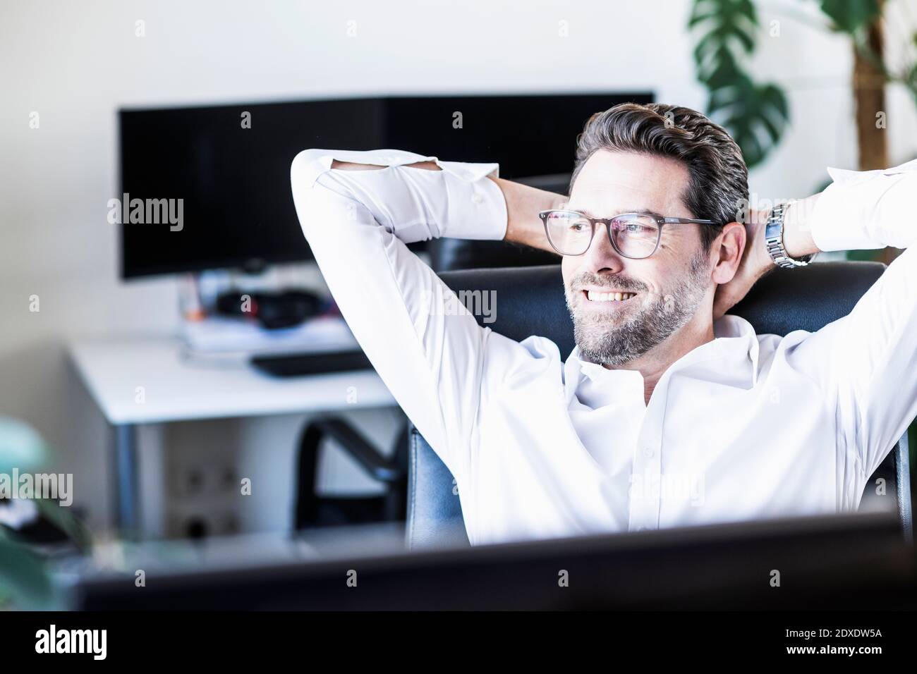 Homme d'affaires assis avec les mains derrière la tête au bureau Banque D'Images