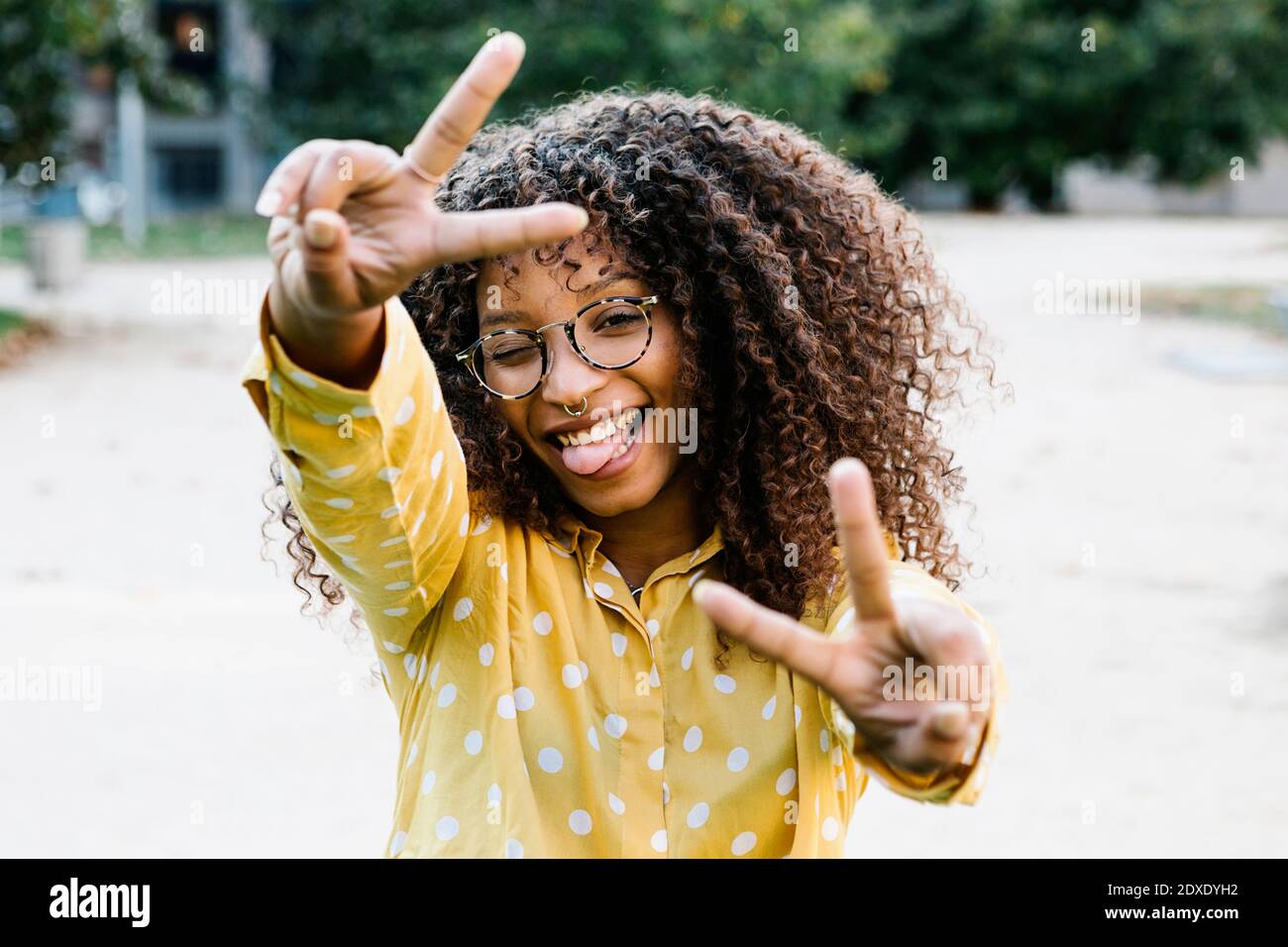 Femme insouciante montrant le geste de paix en se tenant debout sur le sentier Banque D'Images