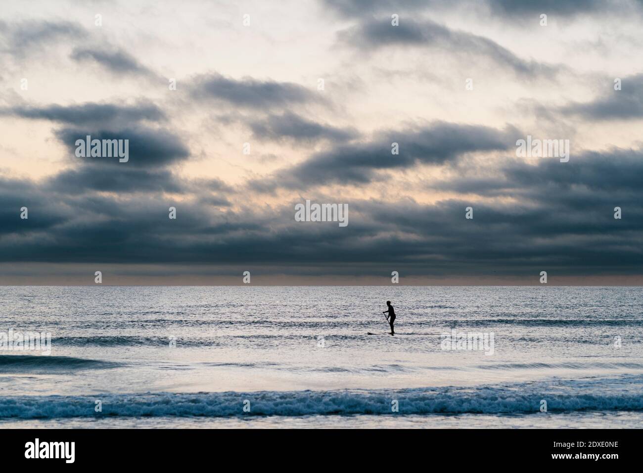 Une paddleboarder femelle surfant sur la mer à l'aube Banque D'Images