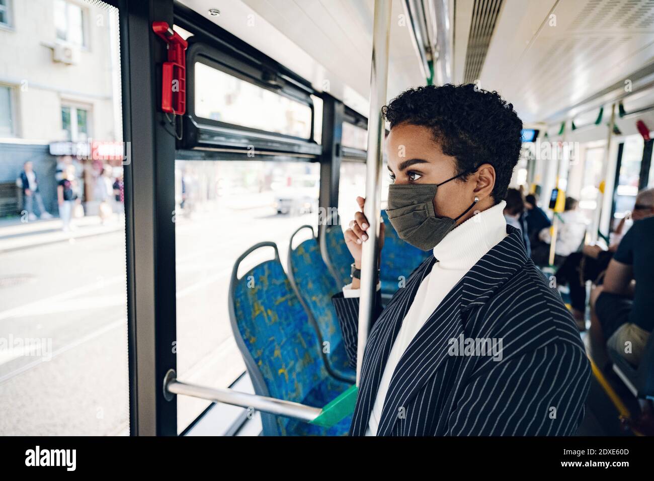 Jeune femme d'affaires regardant à travers la fenêtre pendant qu'elle voyage dans le bus pendant COVID-19 Banque D'Images Jeune femme d'affaires regardant à travers la fenêtre pendant qu'elle voyage dans le bus pendant COVID-19 Banque D'Images