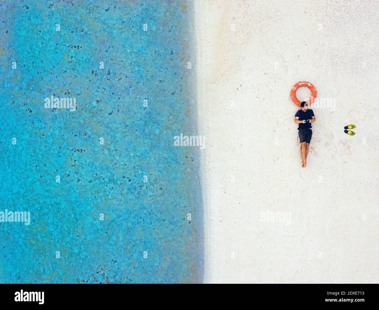 Mâle adulte moyen couché avec anneau gonflable à tropical plage Banque D'Images