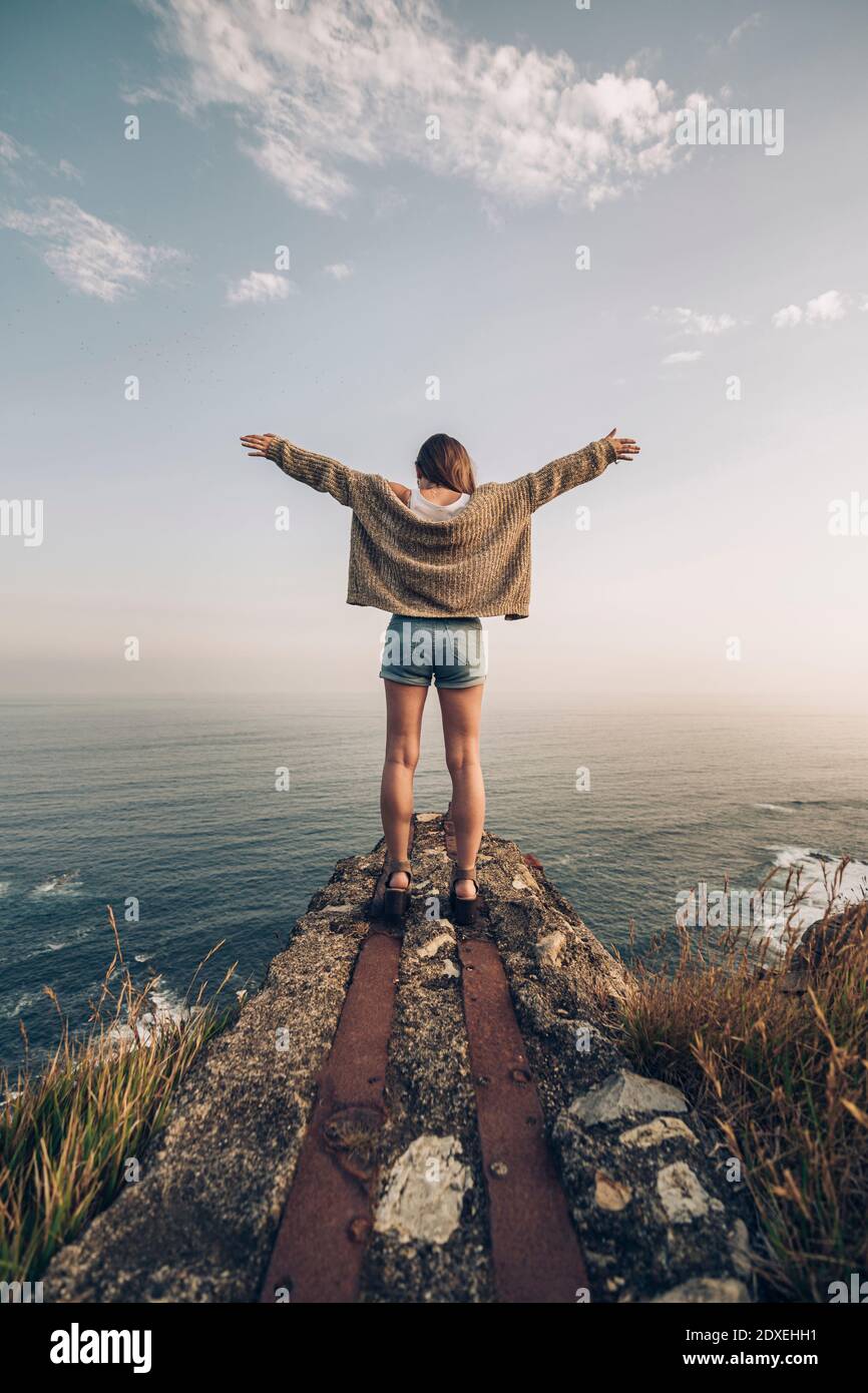 Jeune femme debout avec les bras étirés contre le ciel Banque D'Images