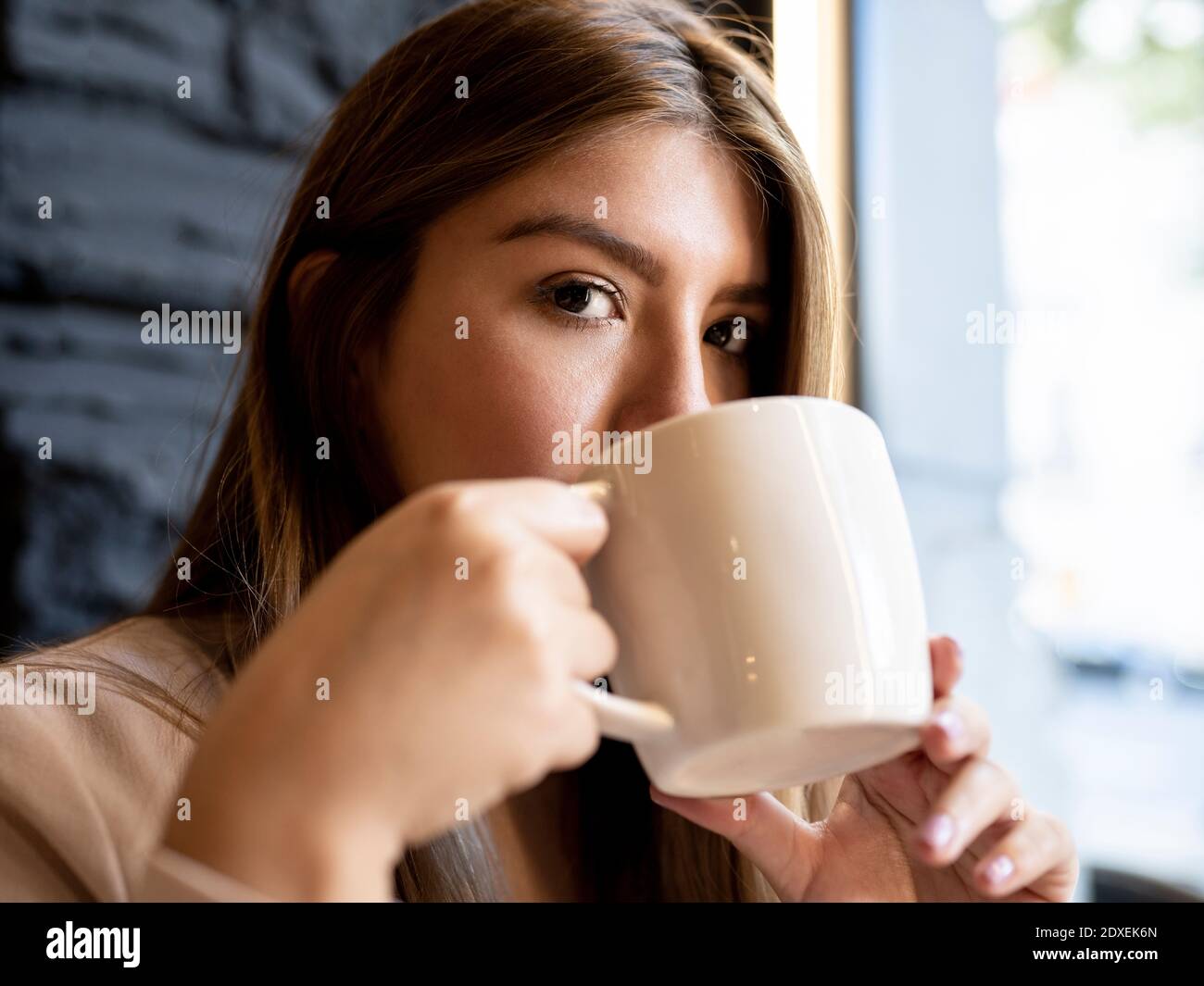 Femme regardant en buvant un café au café Banque D'Images