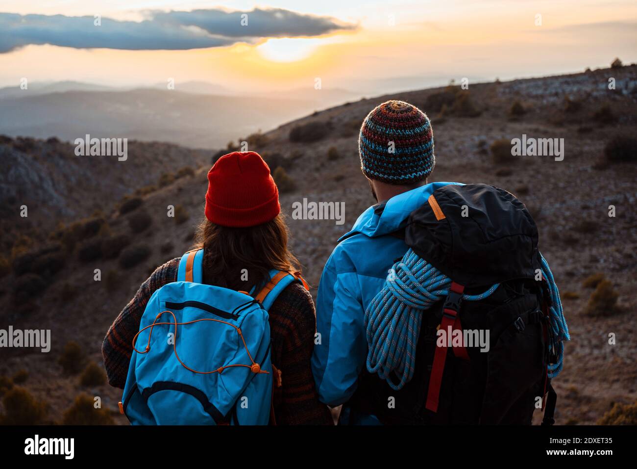 Randonneurs masculins et féminins profitant du coucher de soleil depuis la montagne pendant les vacances Banque D'Images