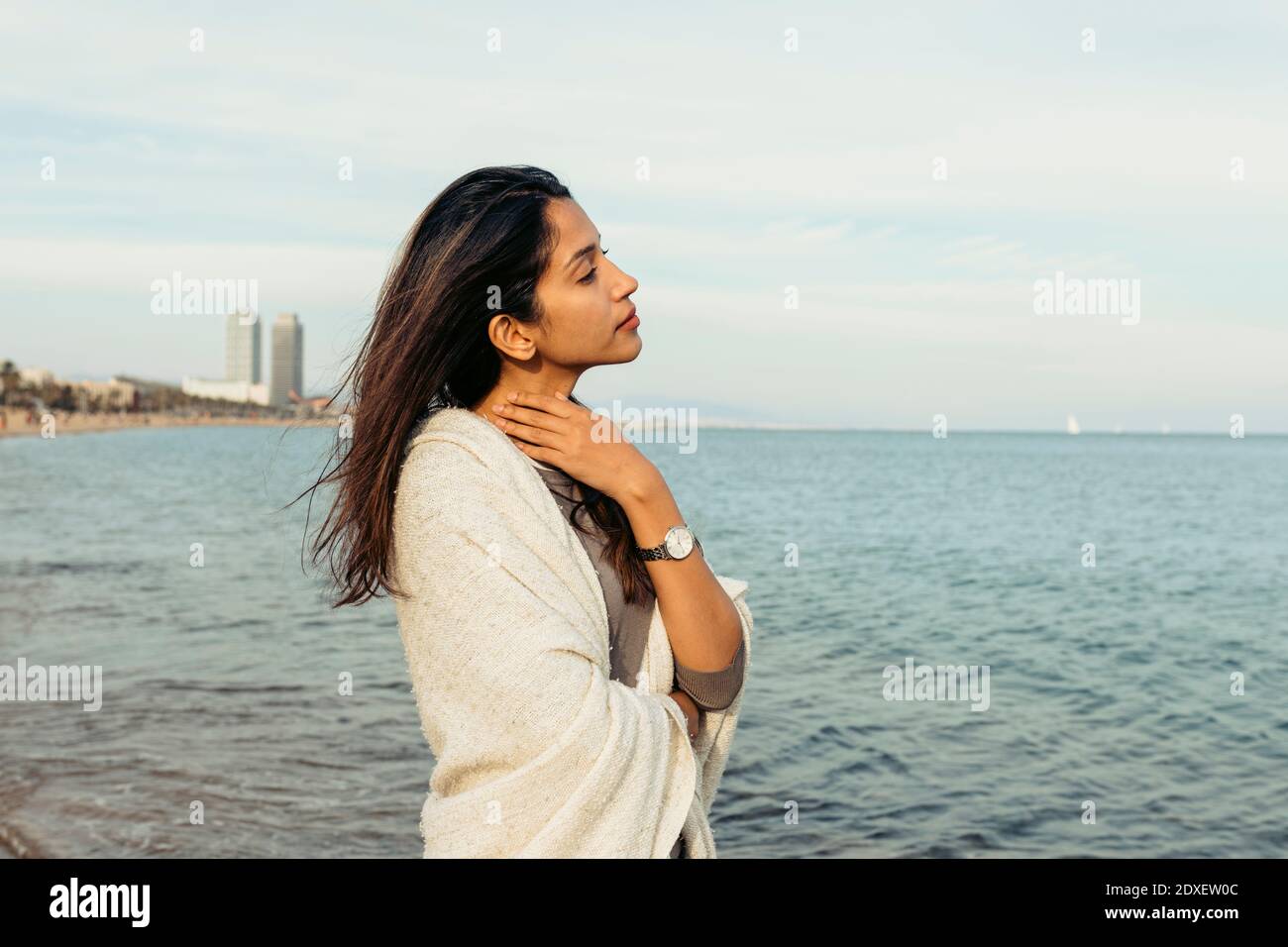 Femme attentionnée regardant loin en se tenant contre le ciel à la plage Banque D'Images