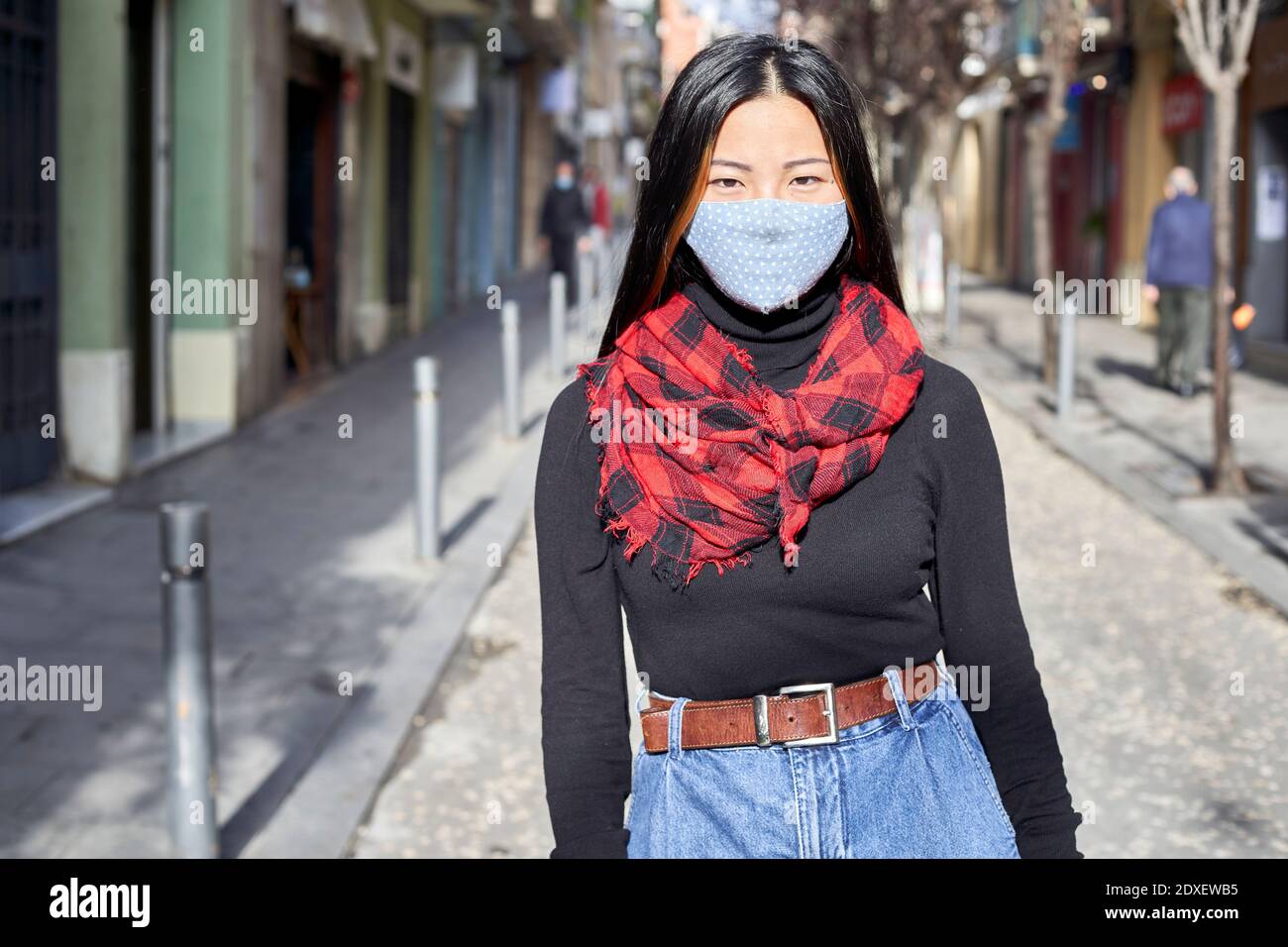 Jeune femme portant un masque de protection debout dans la rue ville Banque D'Images