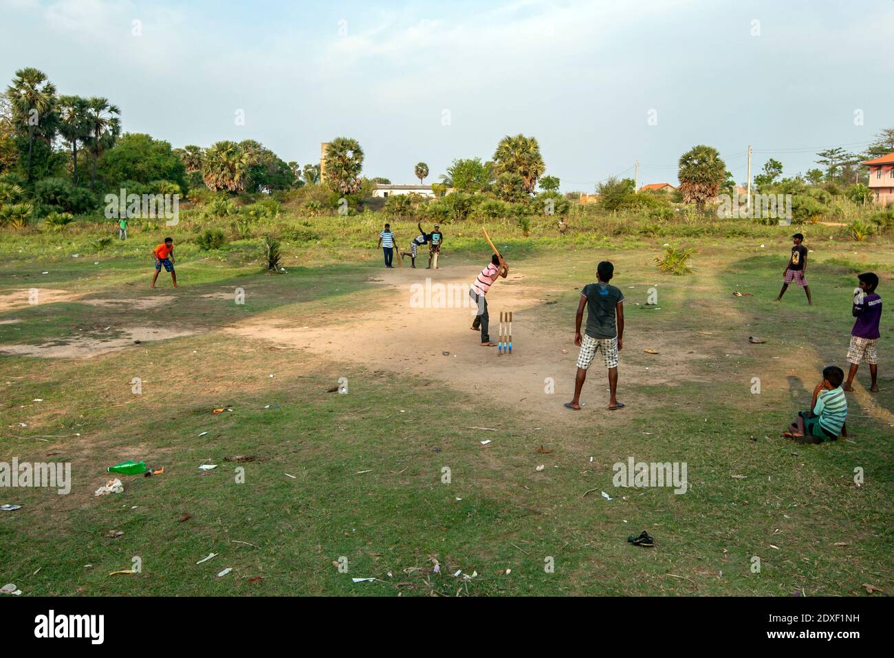 En fin d'après-midi, des hommes jouent au cricket sur un terrain de terre à Uppuveli, sur la côte est du Sri Lanka. Banque D'Images