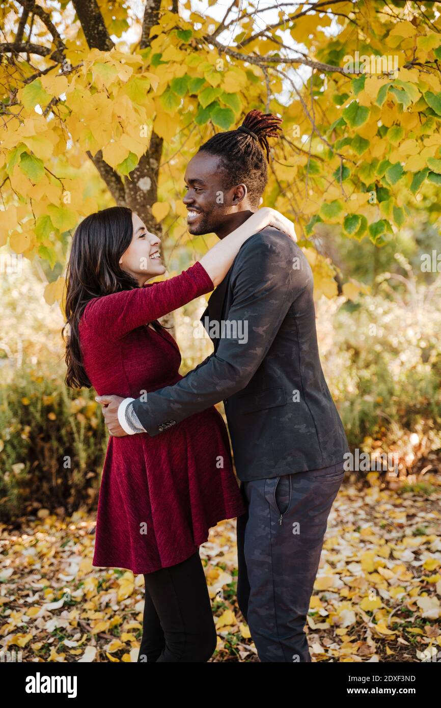 Un couple multiethnique souriant s'embrassant les uns les autres dans le parc pendant automne Banque D'Images