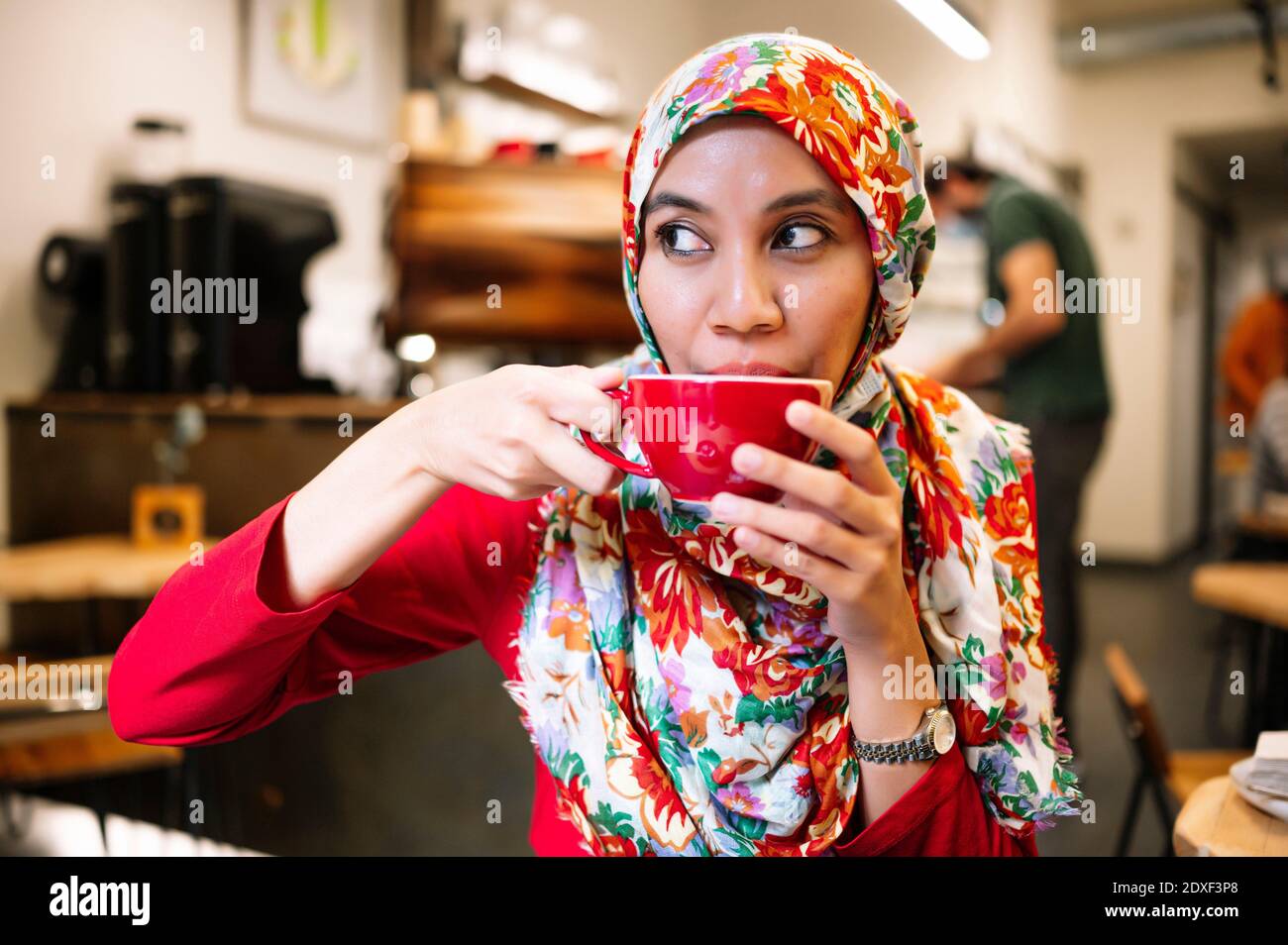 Femme malaisienne qui regarde loin tout en buvant un café dans un café Banque D'Images