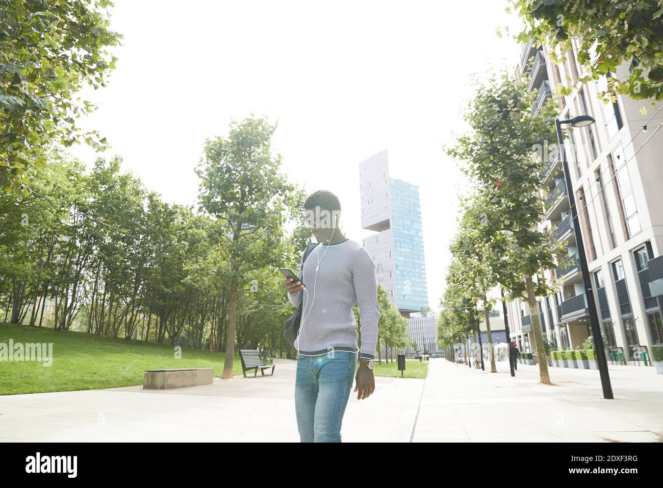 Homme d'affaires écoutant de la musique avec des écouteurs intra-auriculaires tout en marchant sentier de la ville Banque D'Images