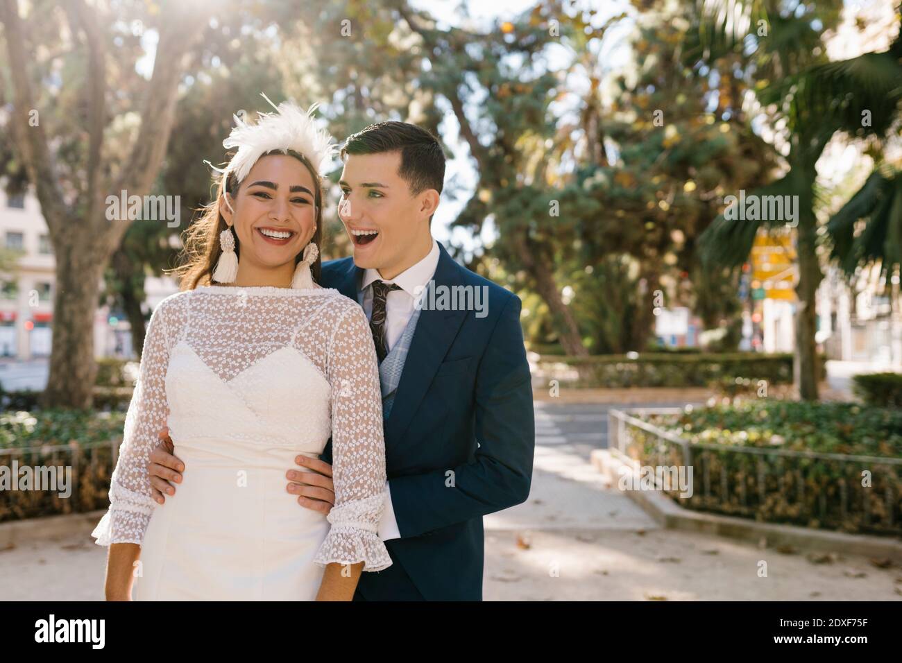 Un marié souriant qui embrasse la mariée en se tenant au parc Banque D'Images