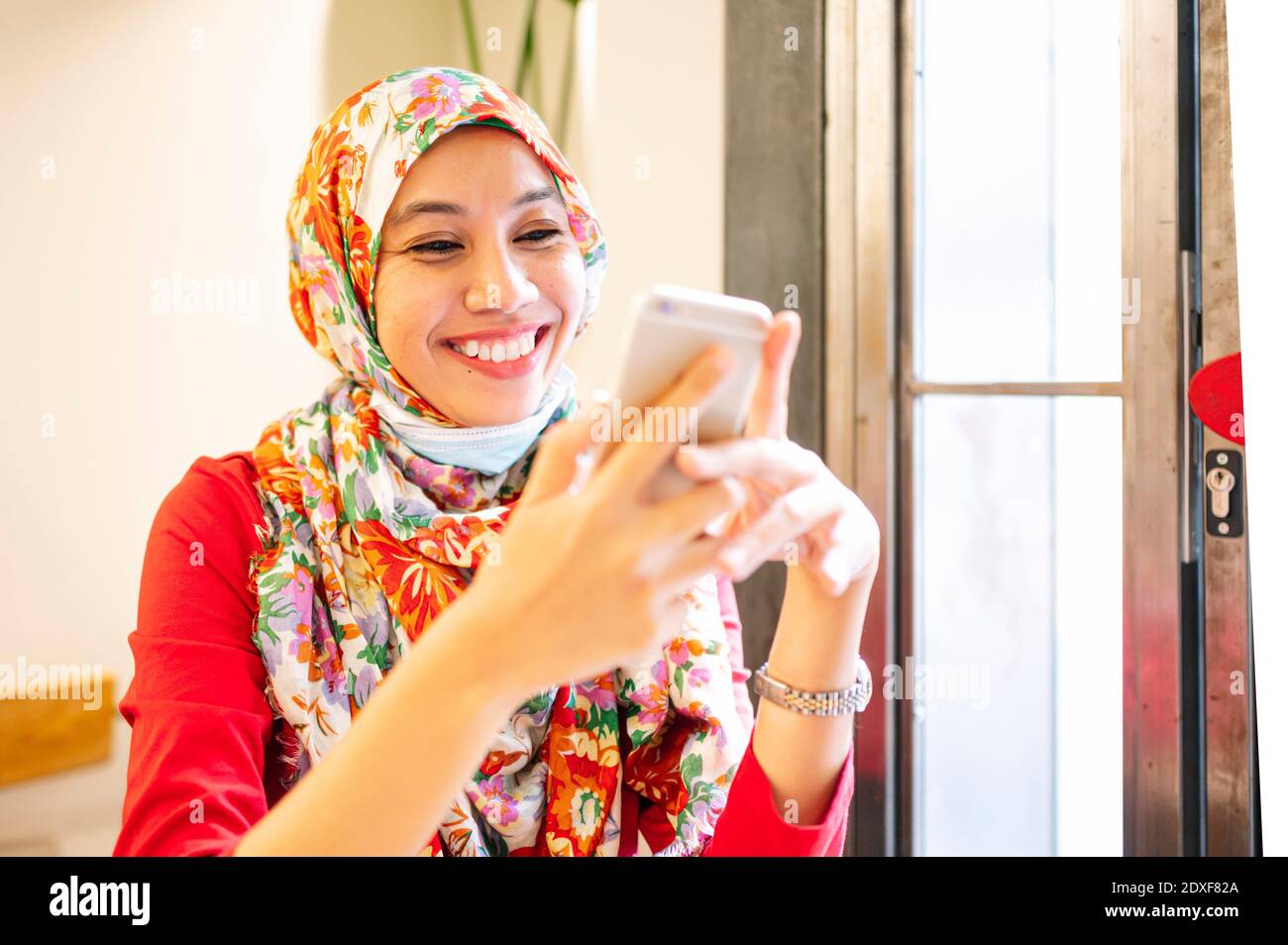 Bonne femme malaisienne portant le hijab en utilisant un smartphone dans un café Banque D'Images