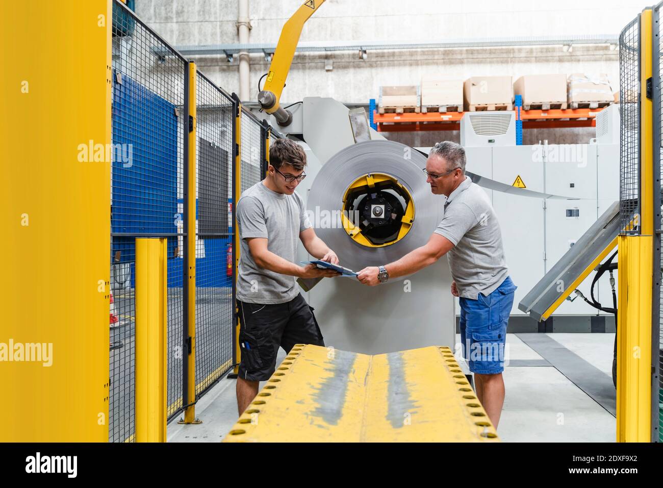 Remue-méninges entre un jeune ingénieur et un travailleur manuel machines en usine Banque D'Images