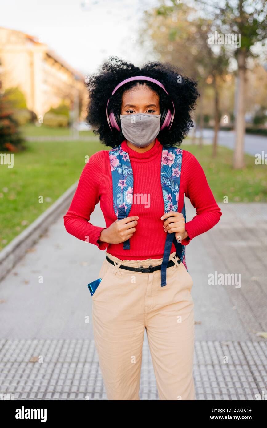 Femme portant un masque de protection et un casque portant un sac à dos pendant debout sur le sentier Banque D'Images