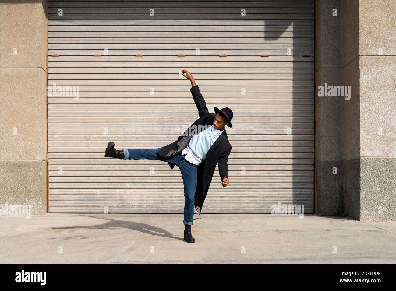 Jeune homme tendance debout sur une jambe tout en dansant contre obturateur Banque D'Images