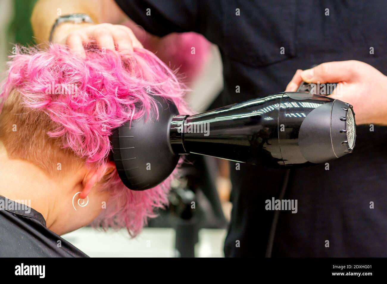 Gros plan du coiffeur séchage des cheveux courts roses ou rouges elle  comprend un sèche-cheveux dans un salon de beauté Photo Stock - Alamy