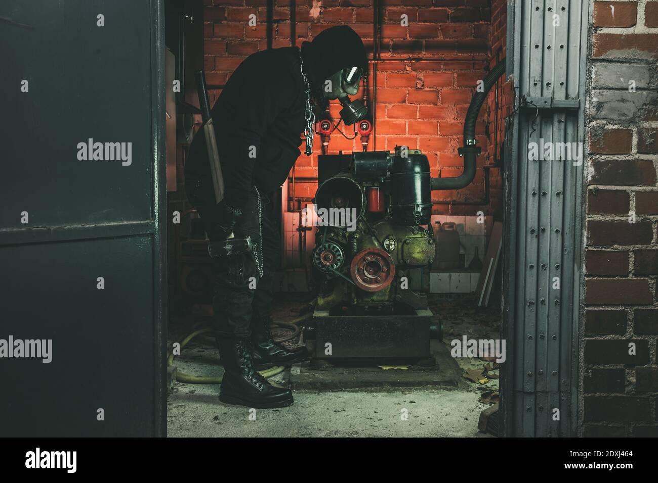 Homme avec un masque à gaz et un marteau dans la salle des machines. Concept de danger nucléaire, biologique et chimique. Banque D'Images