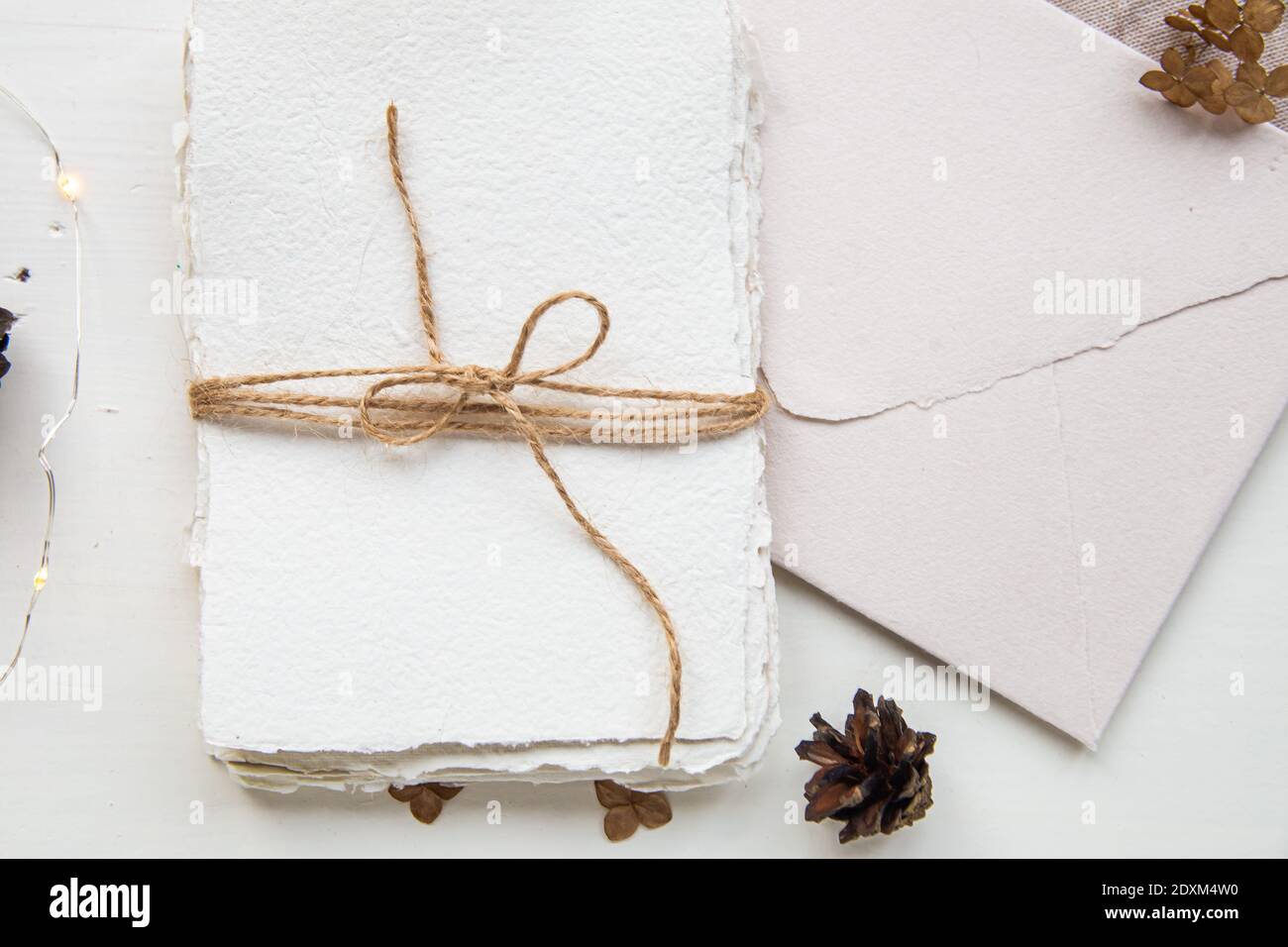 Pose plate style hygge. Liste de souhaits de Noël. Papier fait à la main noué avec des fils artisanaux. Enveloppe de lettre, cônes de pin, fil de métier. Banque D'Images