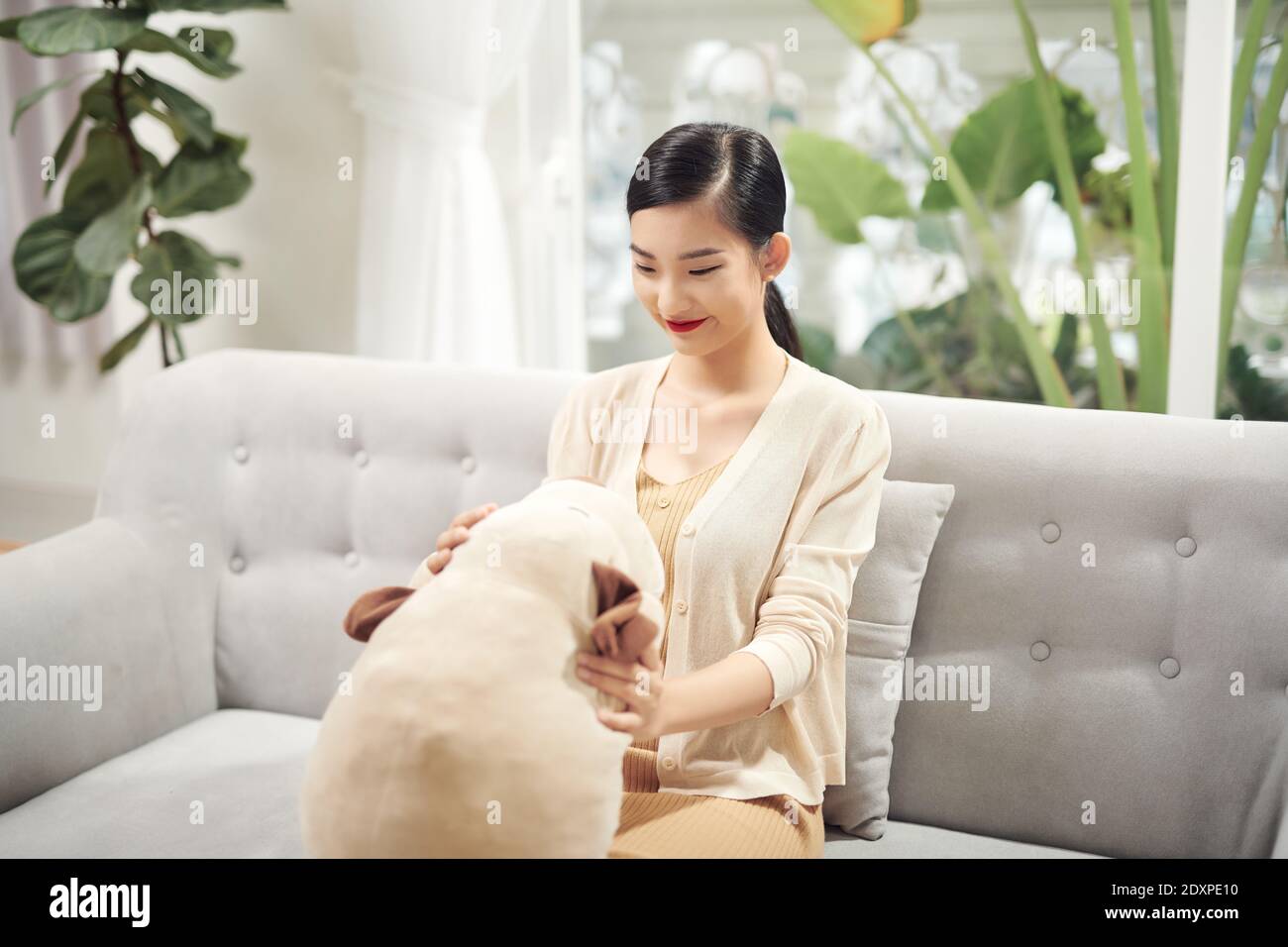 Femme assise sur un canapé avec un chien jouet Banque D'Images