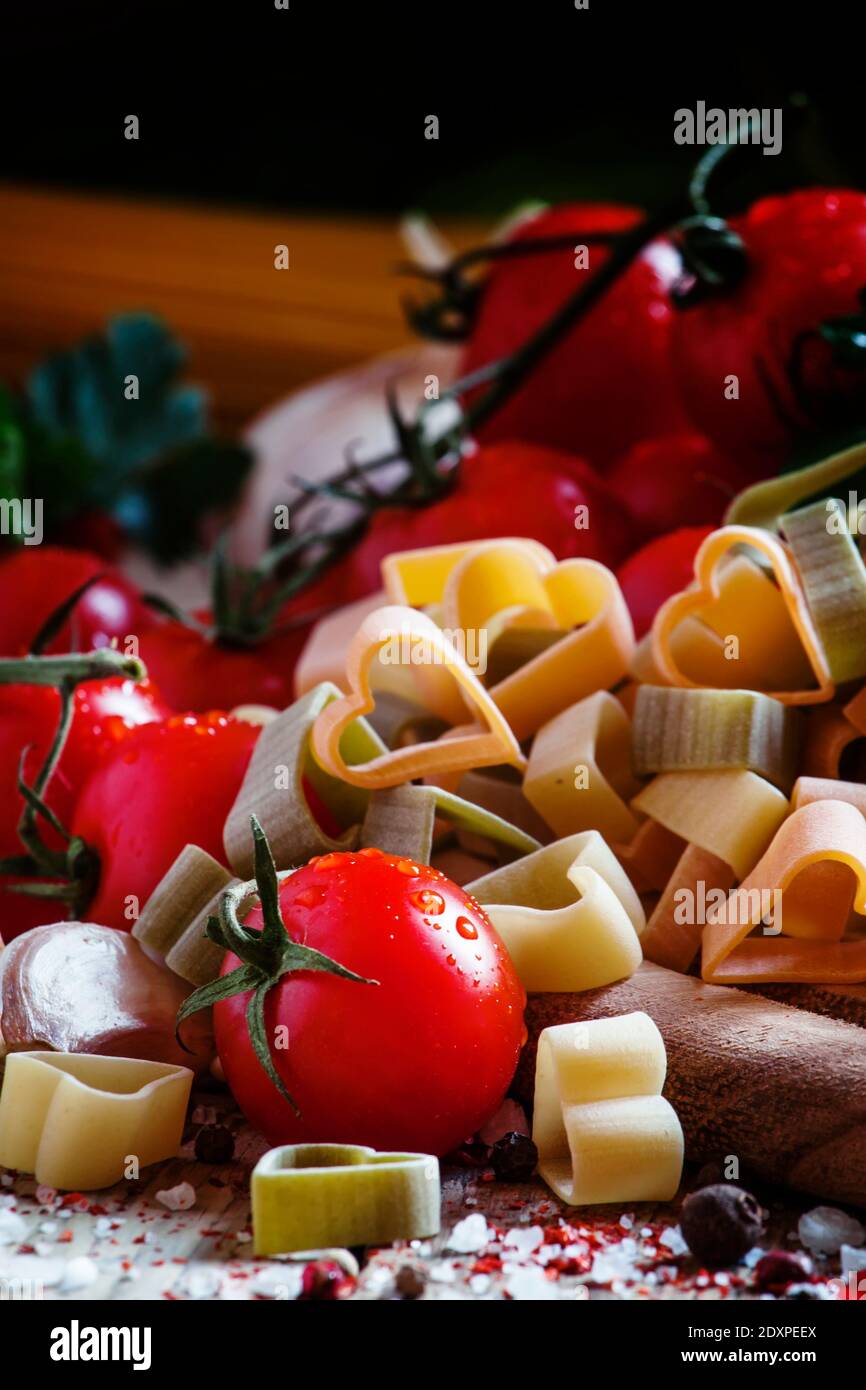 Pâtes tricolores espagnoles corazones en forme de coeurs, tomates cerises, herbes, épices, sel, cuisine méditerranéenne, sélectif Banque D'Images