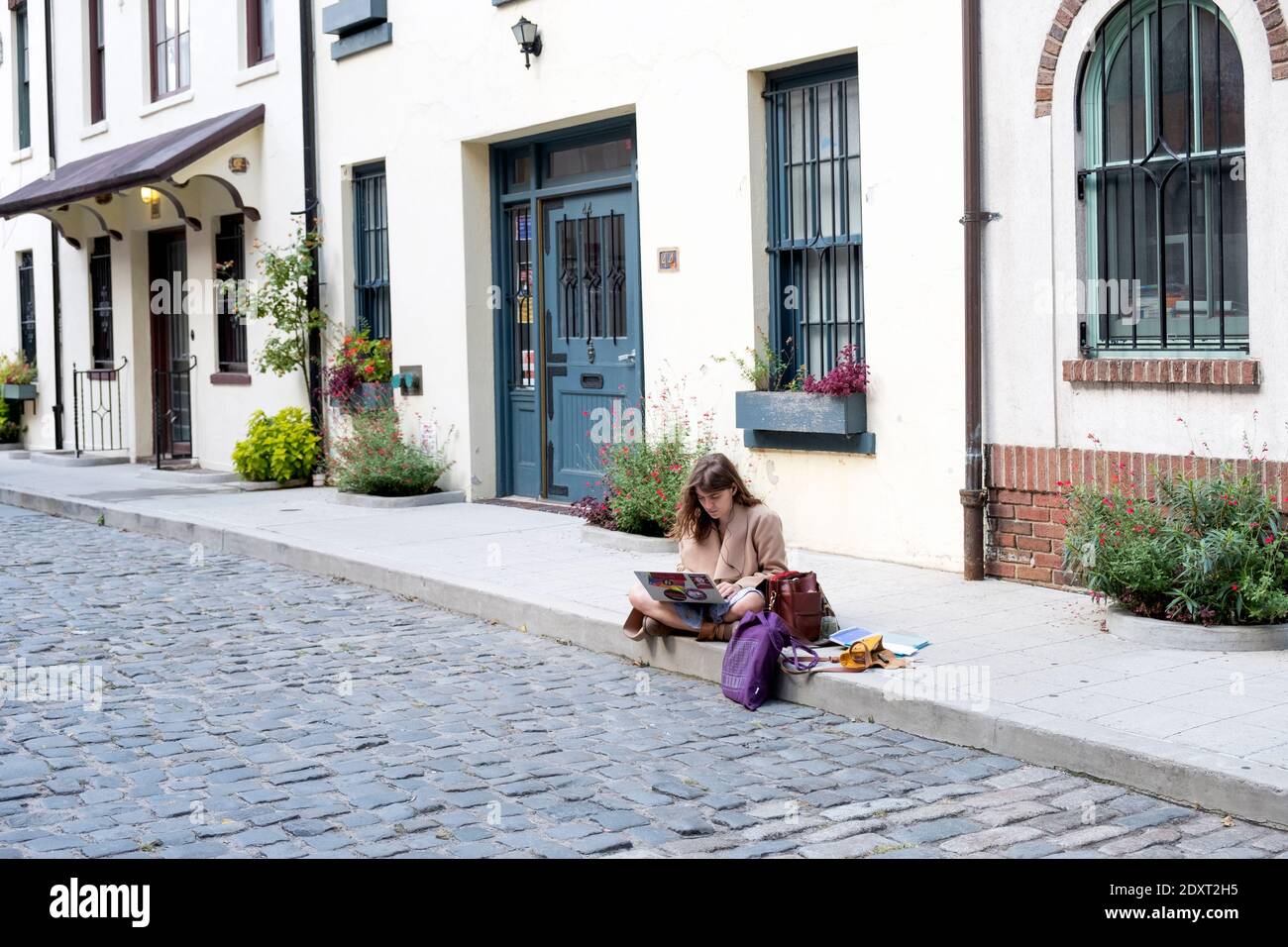 Une femme lisant de son ordinateur sur Washington Mews, une rue privée fermée dans Greenwich Village, Manhattan, New York City Banque D'Images