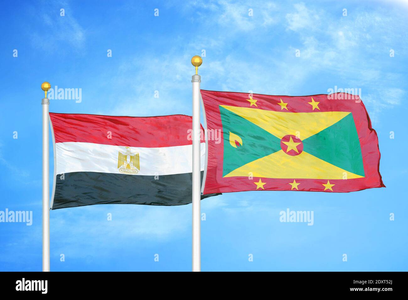 Égypte et Grenade deux drapeaux sur les mâts de drapeaux et bleu nuageux ciel Banque D'Images