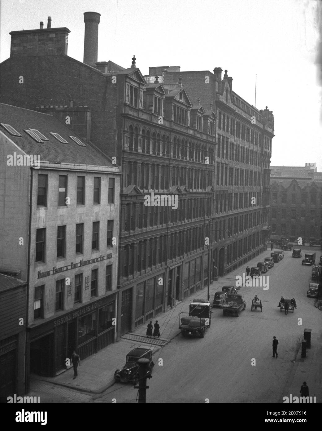 Années 1930, historique, Glasgow, Écosse, Royaume-Uni. Vue en hauteur de l'activité dans une rue du centre-ville. Sur la gauche de la photo se trouve le bâtiment d'œuvres de Sisson Brothers & Co, un fabricant de paiint, fondé en 1803 à Bankside, Hull, Angleterre, sous le nom de Sisson Paints, devenant Sisson Brothers en 1827. À la fin du XIXe siècle, ils ont ouvert des dépôts dans d'autres parties du Royaume-Uni, y compris Glasgow. En 1956, Reckitt & Colman de Hull, la célèbre compagnie de moutarde, a racheté l'entreprise. En 1969, Sisson peint n'était plus et l'entreprise a cessé et son complexe d'usines de Hull a fermé. Banque D'Images