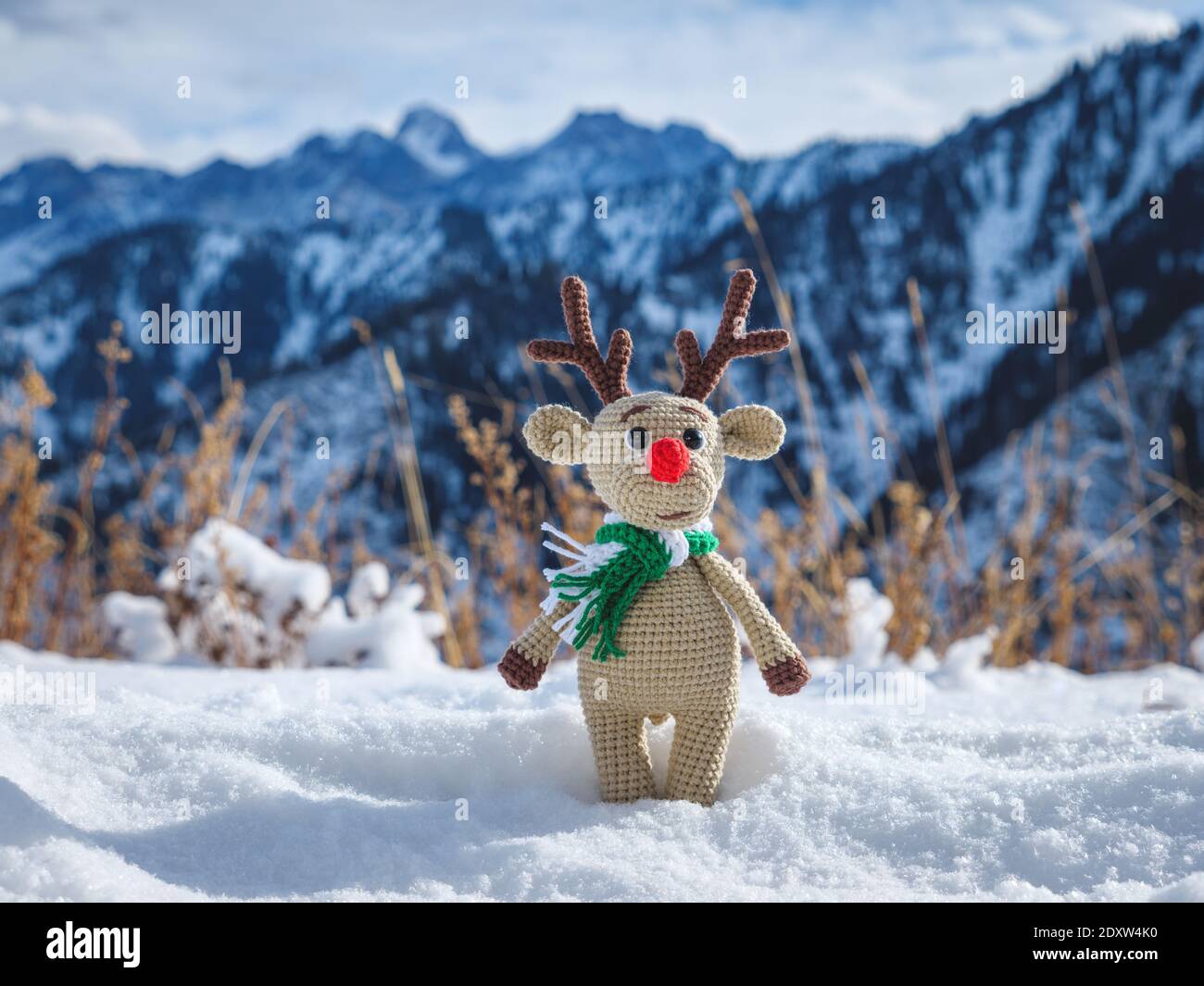 Cerf jouet en hiver dans les montagnes. Jouet arbre de Noël tricoté fait à la main Banque D'Images
