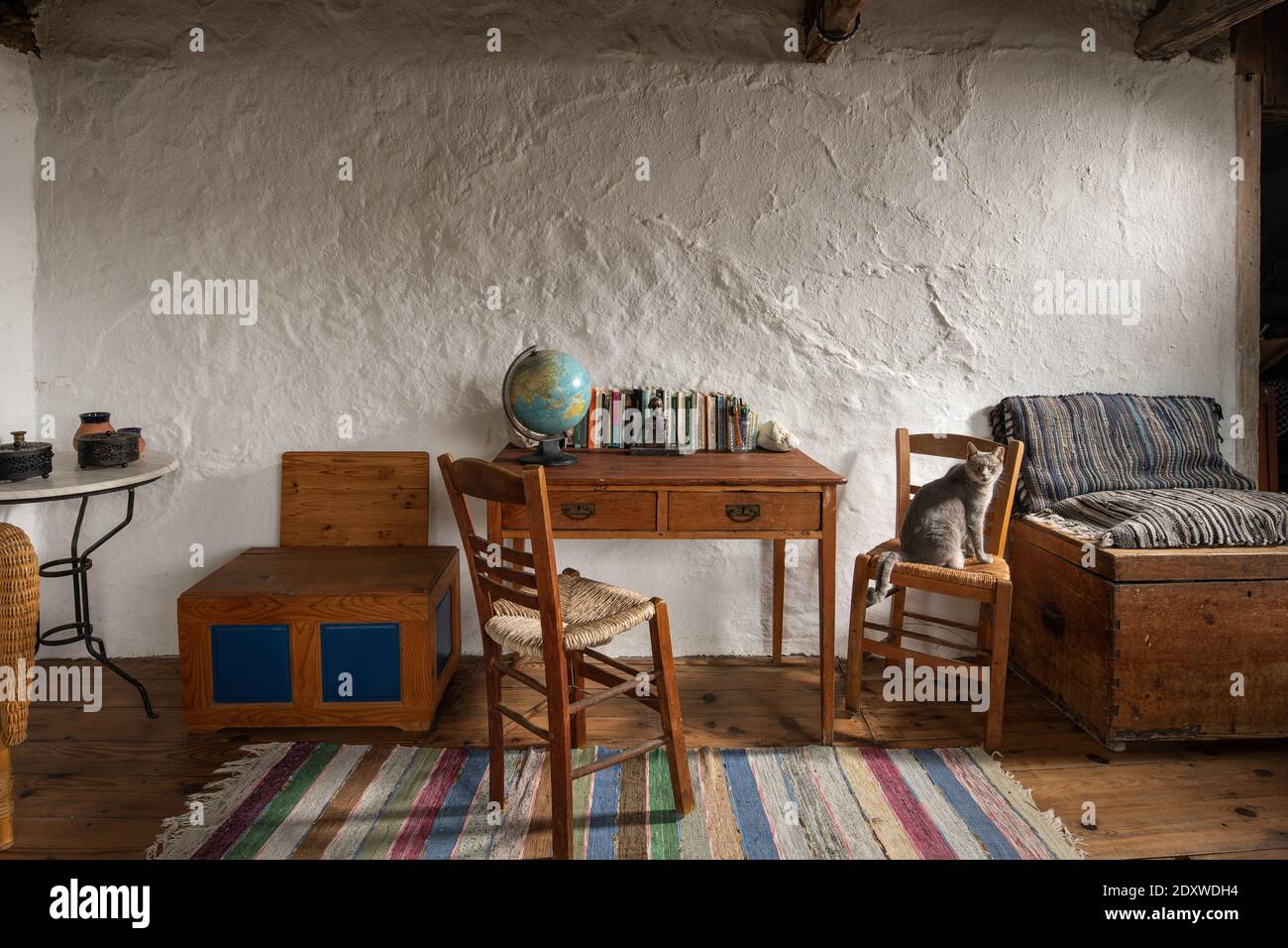 Vue avant de l'intérieur d'une chambre vintage dans une maison de campagne  traditionnelle du village. Mobilier artisanal ancien, bureau d'école,  chaises en bois, coffre sur stuc wa Photo Stock - Alamy