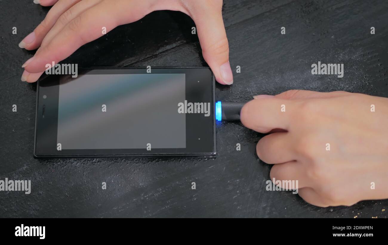 Woman's hand de brancher le câble de charge de la foudre noire smartphone en Banque D'Images