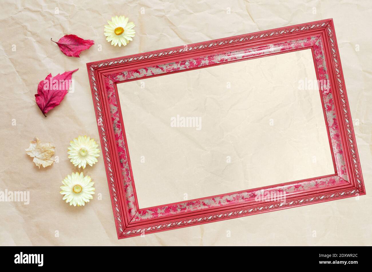 Cadre photo avec papier propre pour le texte, les feuilles séchées et les fleurs sur un fond de papier beige froissé, vue du dessus Banque D'Images