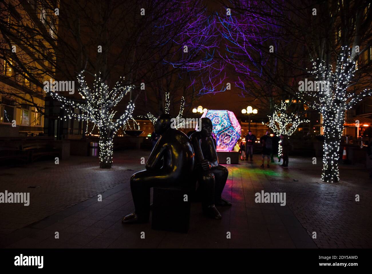 Two Men on a Bench (1995) statue de bronze de Giles Penny à Canary Wharf, Londres, Royaume-Uni. Festival des lumières d'hiver, 2018. Banque D'Images