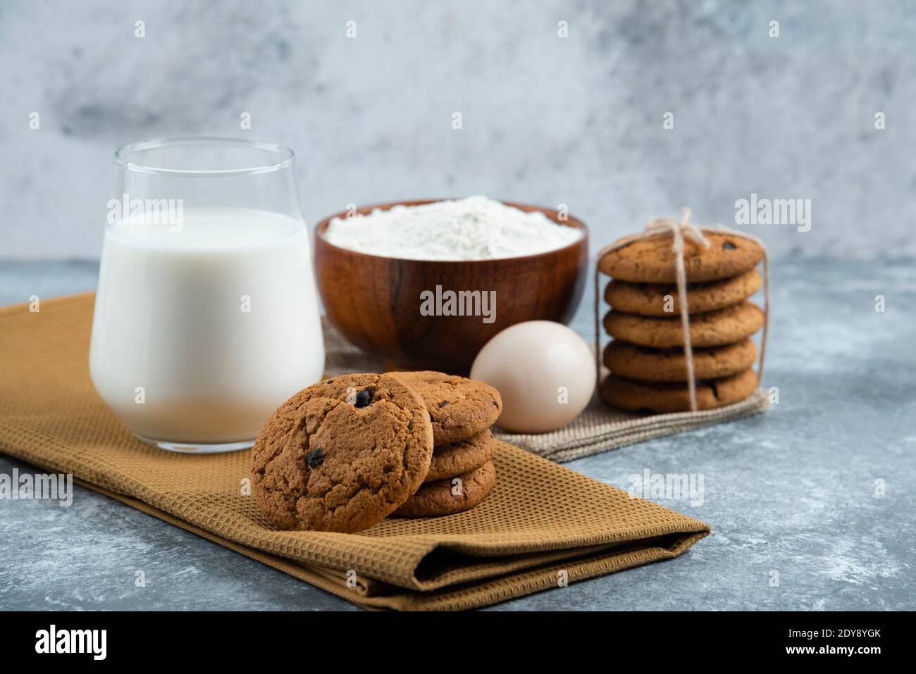 Un verre de lait chaud avec de délicieux petits gâteaux sur un arrière-plan gris Banque D'Images