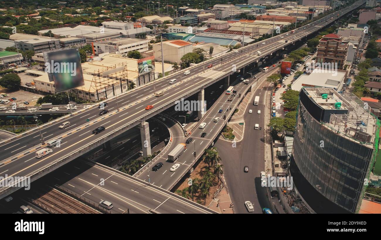 Gratte-ciel moderne sur la route de circulation avec des voitures. Antenne du centre-ville de Manille. Paysage urbain philippin avec panneaux publicitaires sur l'autoroute. Paysage urbain pittoresque de la capitale des Philippines à travers l'autoroute. Banque D'Images