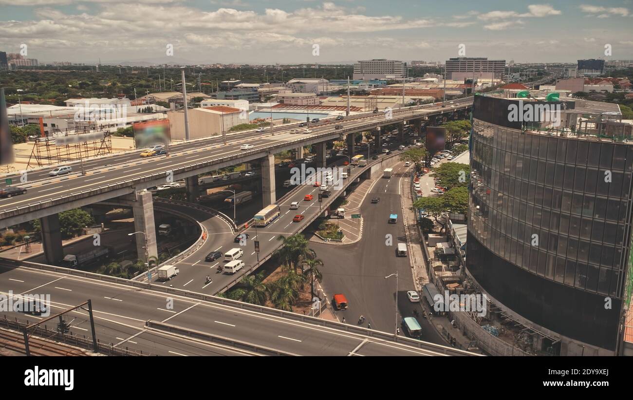 Chaussée de la ville de Manille avec des voitures et des camions à des bâtiments modernes vue aérienne. Paysage urbain avec chalets, gratte-ciel de la circulation en bord de route. Tir de drone cinématographique de la capitale des Philippines, en Asie Banque D'Images